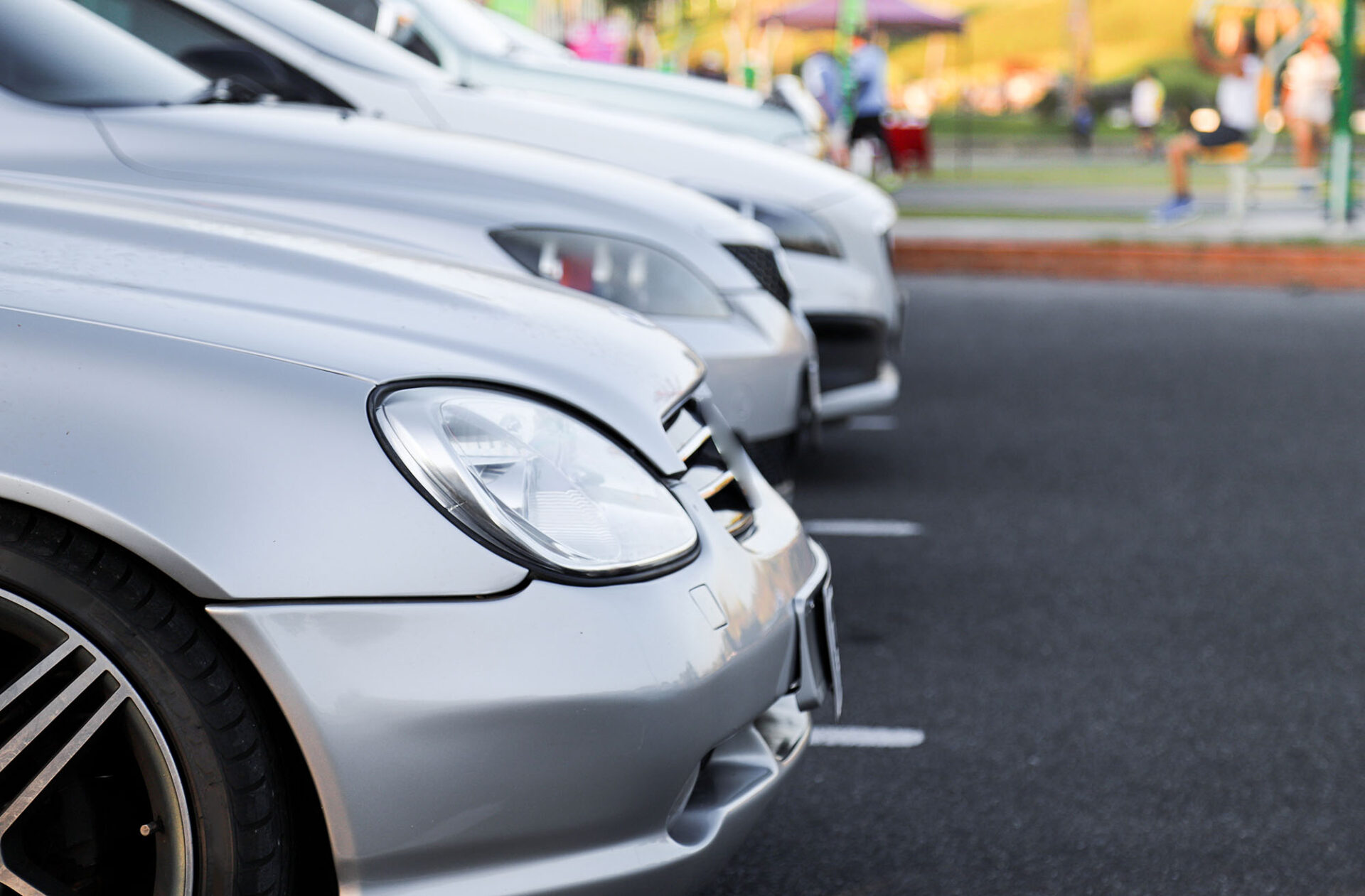 Closeup of front side of bronze car and other cars parking in pa